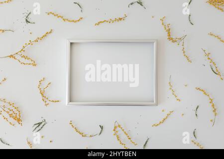 mockup with yellow mimosa flowers and blank photo frame with copy space. Spring, Easter concept Stock Photo