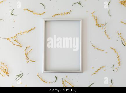 mockup with yellow mimosa flowers and blank photo frame with copy space. Spring, Easter concept Stock Photo