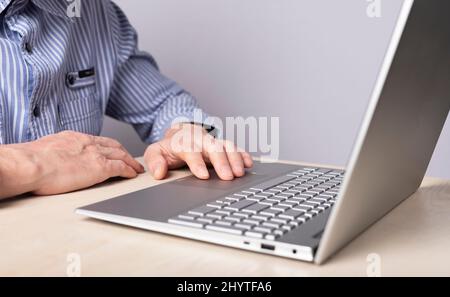 Man hand closeup on laptop touchpad. Using computer for information search, distant work and education, online shopping and booking, playing games and leisure. High quality photo Stock Photo