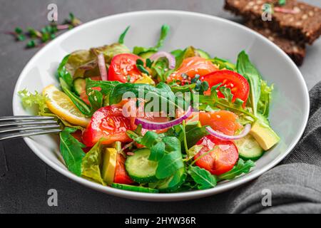 Vegetable salad with salmon and fresh herbs on a dark background. Side view, close-up. Stock Photo