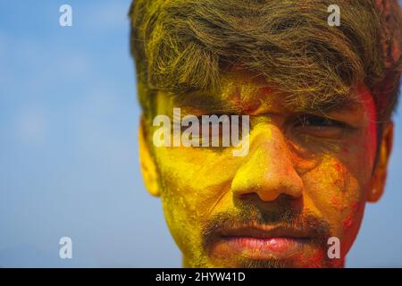 Closeup of the young man's face covered in bright colors. Holi festival. Stock Photo