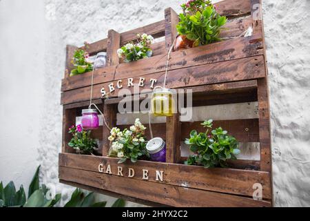 Rustic wood rural ornament hanged on the exterior wall , ornate with different flowers , red , yellow, Green, and glass decor Stock Photo