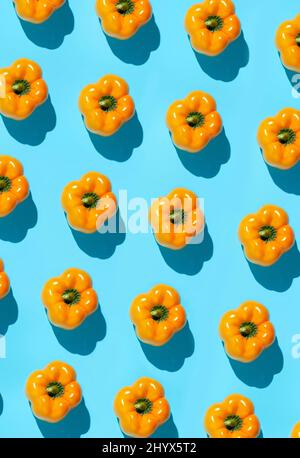 Graphic top view background of fresh yellow vegetables pattern on vibrant blue background, healthy eating and vegan concept Stock Photo
