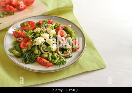 Green vegetables like peas, beans and spinach with feta cheese, braised onions and tomatoes, healthy meal for a vegetarian low carb diet, copy space, Stock Photo