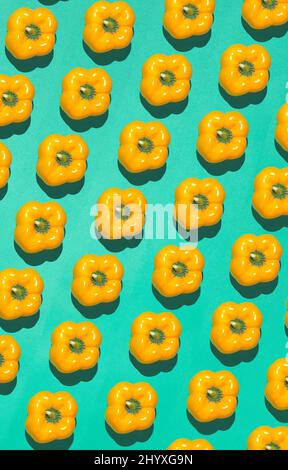 Graphic top view pattern of fresh yellow peppers in diagonal lines on contrasted blue background, healthy eating and vegan concept, copy space Stock Photo