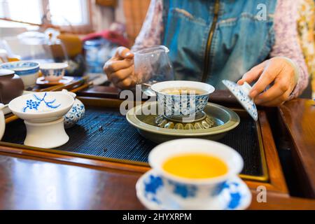 CHINA HANGZHOU Young tea server pours tea from behind his back using  antique long spout teapot Stock Photo - Alamy