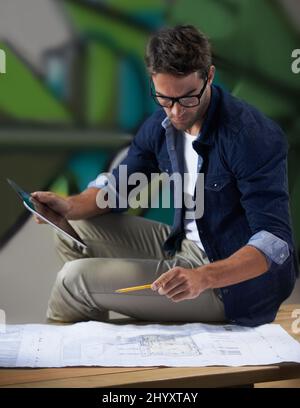 One final look at the plan before the presentation. Shot of a trendy male designer working on building plans at his desk. Stock Photo