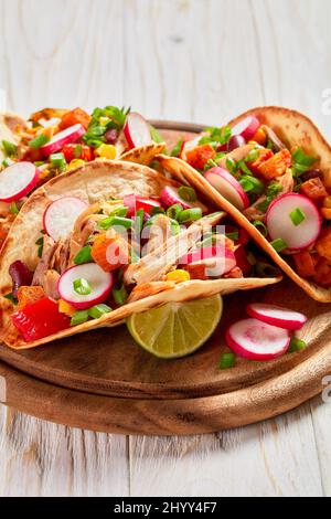 pitacos, mexican tacos with pita bread, spicy pulled chicken meat, red kidney beans, corn, radish, red pepper, roast sweet potatoes and lime on wooden Stock Photo