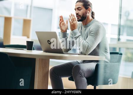 Young businessman having a discussion with his associates during a virtual meeting. Modern businessman attending a video conference while working remo Stock Photo