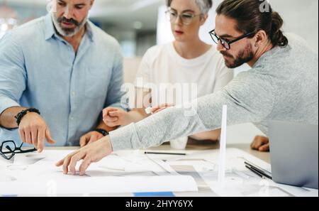Innovative designers working with wind turbine blueprints in a modern office. Group of creative businesspeople having a discussion while working on a Stock Photo