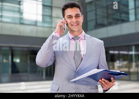 Satisfied businessman with papers talking on phone Stock Photo