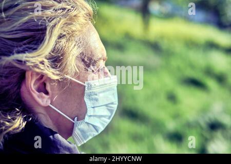 Portrait of a young mature caucasian blonde woman outdoor with face mask. Pandemia concept. Stock Photo
