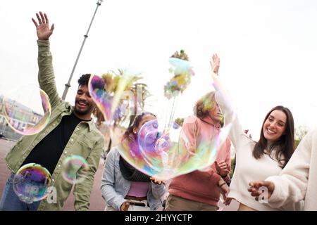 Happy party with soap bubble. Young adult people dancing outdoors. Group of friends having fun Stock Photo