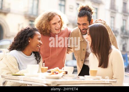 Two female friends having breakfast on the terrace of the bar while 2 guys come over to flirt. Stock Photo