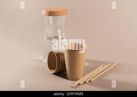 Disposable paper tableware. Cups and straws on beige background. Plastic free and zero waste concept. Stock Photo