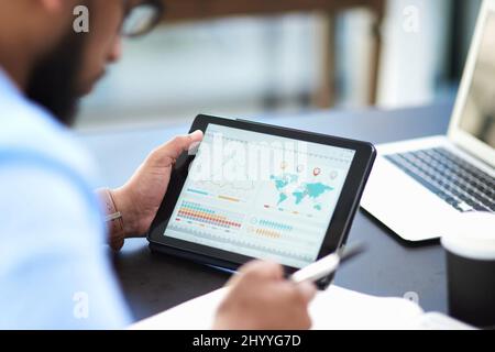 Its important to monitor sales data. Cropped shot of an unrecognizable businessman sitting alone in his office and using a digital tablet. Stock Photo