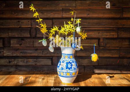 Still life with easter decoration, ceramic vase with easter eggs on twigs of forsythia. Stock Photo