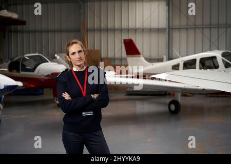 Young pilot posing in the hangar surrounded by airplanes. Stock Photo