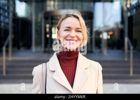 Middle-aged Caucasian businesswoman looking into camera smiles. Beautiful 40-50 years old cheerful lady smiling for the successes of work. Stock Photo
