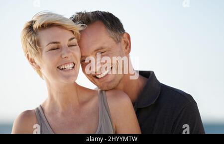 Making each other laugh. Shot of a mature couple enjoying a day at the beach. Stock Photo