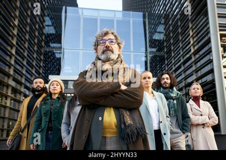 The director of the company poses with his team in front of the corporate building. Business people follow the manager leader to success. Stock Photo