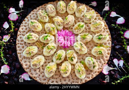 Truffle mousse on apple around mauve flower on Swedish crispbread decorated with dried cranberries and flower petals Stock Photo