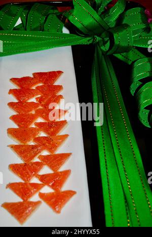 Smoked salmon on toast ocktail hors d'oeuvre served on white linen on tray decorated with green Christmas ribbon Stock Photo