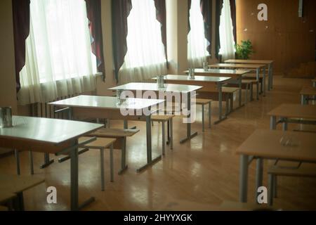 Tables in school canteen. Tables with benches stand in row. Lunch room. School room. Breakfast place for students. Stock Photo