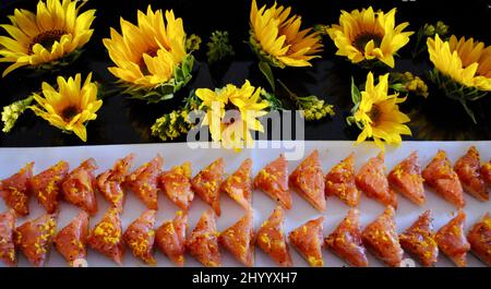 Smoked salmon canapé cocktail hors d'oeuvre on white napkin on tray decorated with sunflowers. Stock Photo