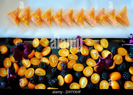 Smoked salmon with orange peel and fresh pepper cocktail hors d'oeuvre on tray decorated with kumquats, blackberries and purple orchids Stock Photo