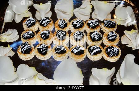 Black caviar on small blini cocktail hors d'oeuvre on tray decorated with white rose petals Stock Photo