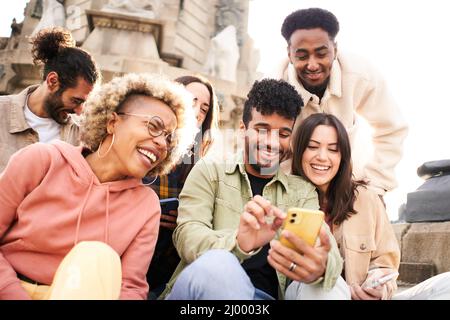 Group of people watching video on the mobile phone. Smiling friends using phone and laughing. Youth culture and technology concept Stock Photo