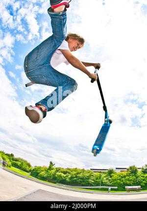 young boy with scooter is going airborne Stock Photo