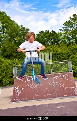 young boy with scooter is going airborne Stock Photo