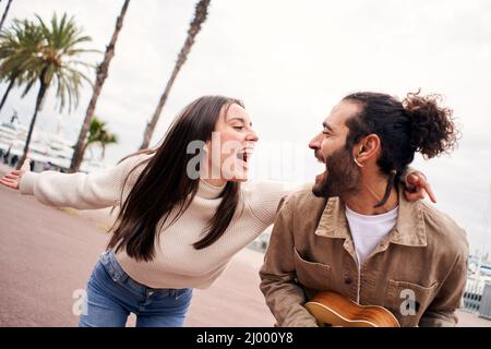Happy couple having fun singing and dancing outdoors Stock Photo