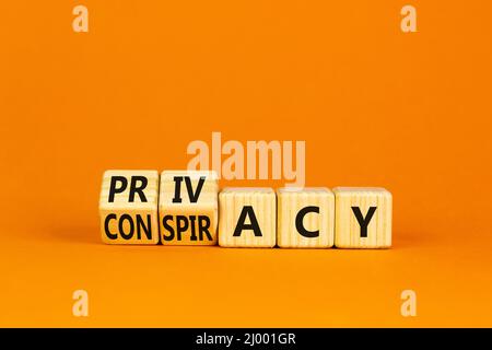 Privacy or conspiracy symbol. Turned wooden cubes and changed the word Conspiracy to Privacy. Beautiful orange table orange background. Business priva Stock Photo