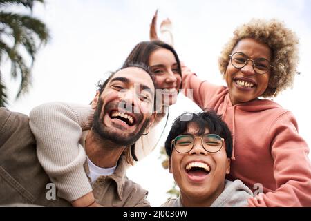 Group of young people looking at the camera outdoors. Happy smiling friends hugging. Concept of community and youth lifestyle Stock Photo