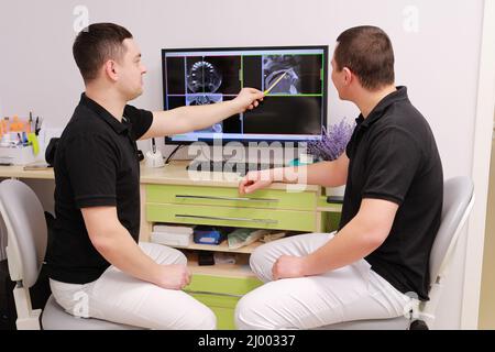 two young dentists are discussing and looking dental problems at x-ray image on computer screen. Healthy teeth and medicine concept. Stock Photo