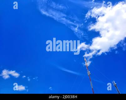 Two antennas, towers of a mobile operator against a blue sky. Blue sky with beautiful white clouds. Antennas for mobile communication, for mobile phon Stock Photo