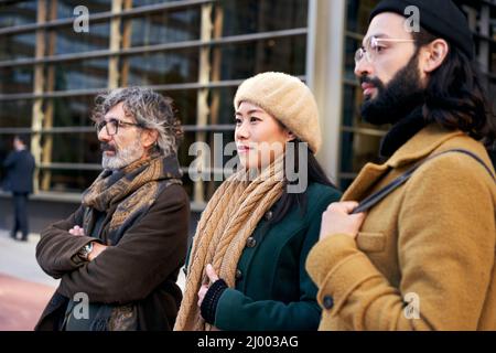 A multi-ethnic group of three people of different ages in a business center posing for a photo. Stock Photo
