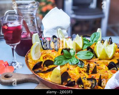 Close-up of home made paella, traditional and specific food made in Spain. Decorated with shrimp, mussels, calamari, lemon and basilic. Traditional Sp Stock Photo