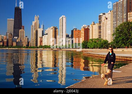 A young woman walks her dog along North Avenue Beach in Chicago Stock Photo