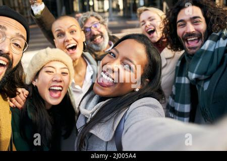 Business woman taking selfie outdoors with a group of diverse colleague people. Smiling cheerful happy photo of a co-workers outdoors Stock Photo