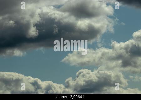 puffy storm clouds gathering against blue sky Stock Photo