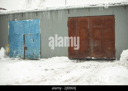 Garage door in winter. Entrance to warehouse. Production room. Rusty doors. Stock Photo