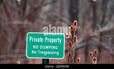 Signboard with the text Private Property No Dumping No Trespassing by dry plants Stock Photo