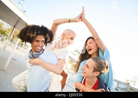 Friends piggyback having fun together. Multiracial young people stacking hands. Stock Photo