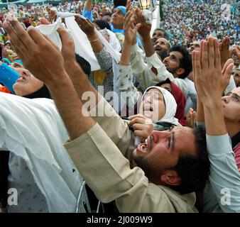 Kashmiri Muslims raise their hands and pray as the grand priest of the historic Hazratbal mosque displays holy relic of Prophet Muhammad, in Srinagar, Kashmir. The shrine is considered to be the most revered shrine by Kashmiri Muslims and every year thousands of devotees participate in the night-long prayers on the occasion of Mehraj-ul-Alam festival. July 31, 2008. Stock Photo