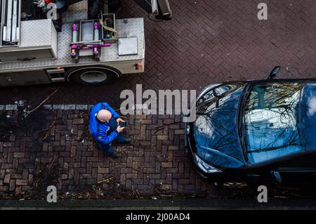 Amsterdam, The Netherlands February 25, 2022: A parking official writing a fine on his phone before towing the car in Amsterdam, The Netherlands Stock Photo