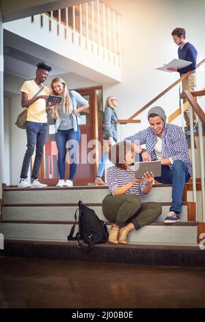 Make use of all the tools at your disposal. Shot of a university students using a digital tablet on the staircase at campus. Stock Photo